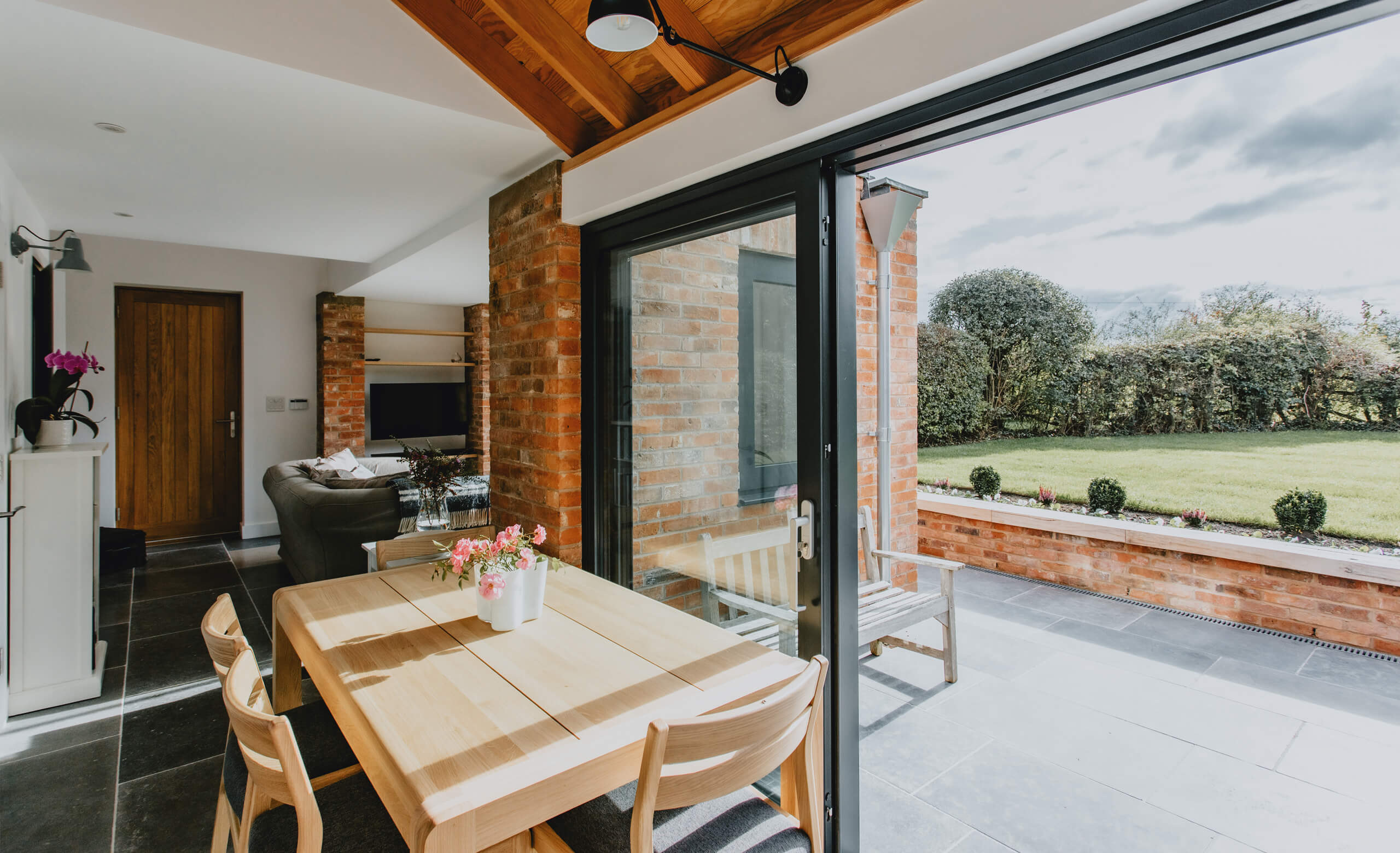 Dining area opening onto the garden through slim aluminium sliding doors
