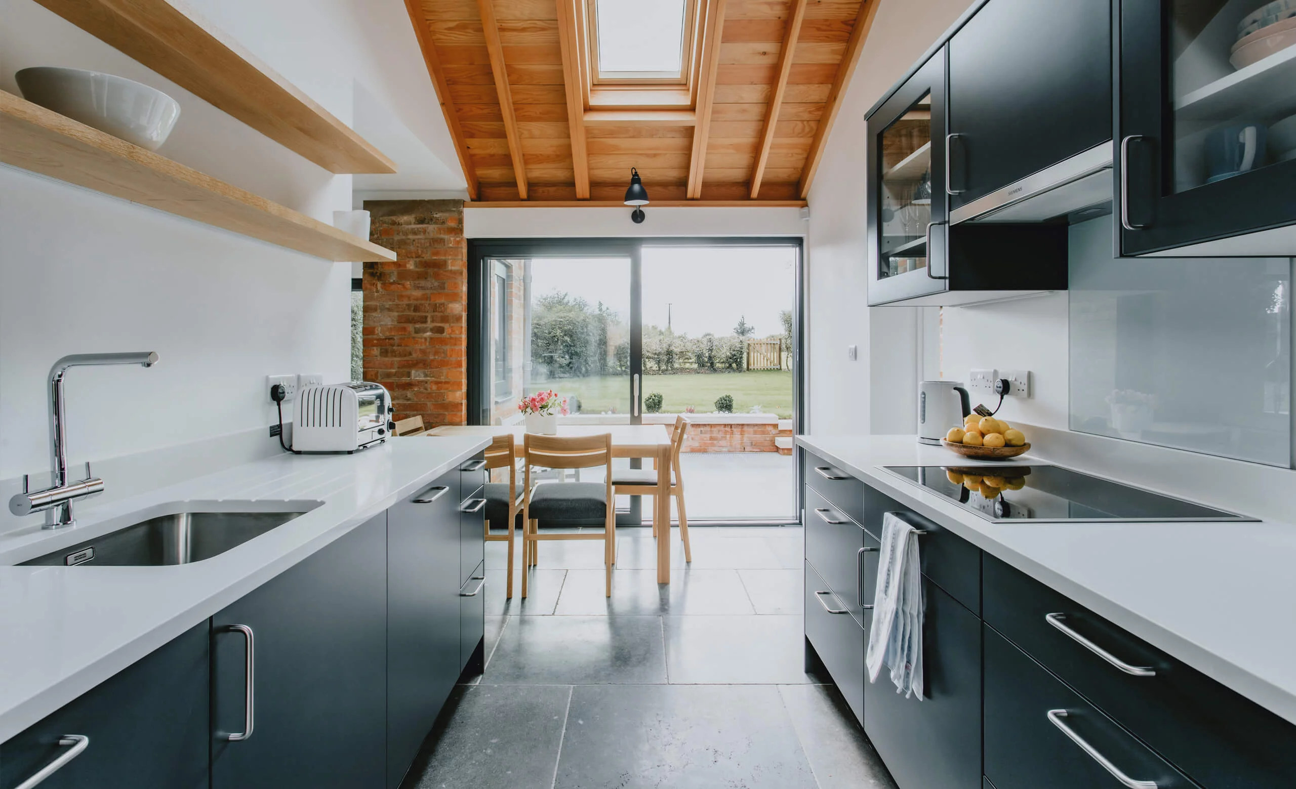 Galley kitchen leading to large aluminium sliding doors and the garden